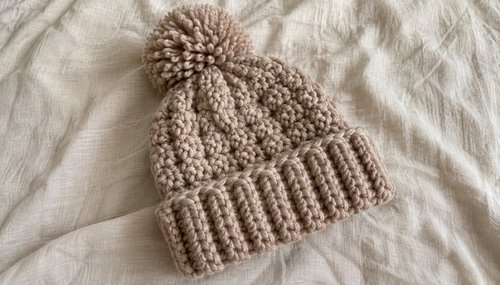Flat lay of a finished crochet beanie with a ball of super bulky yarn