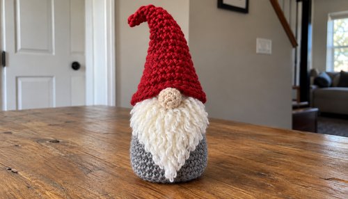 Crochet Christmas gnome amigurumi with tall red hat and fluffy white beard