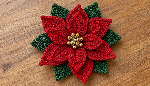 Finished red crochet poinsettia flower with green leaves on a plain background