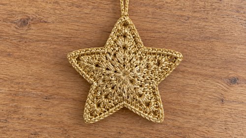 Finished gold crochet star ornament on a plain background